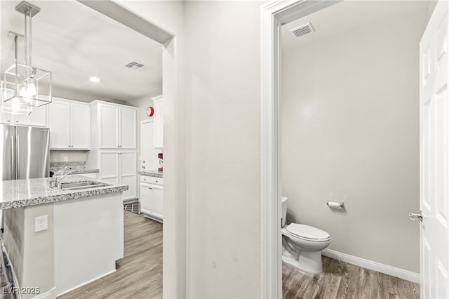 160 Lomita Heights Dr, Las Vegas, NV 89138 - kitchen featuring light wood-style flooring, white cabinetry, light stone countertops, hanging light fixtures, and stainless steel refrigerator