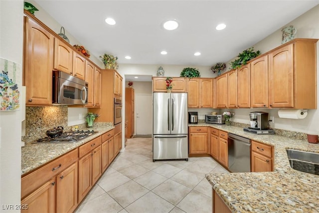 kitchen with appliances with stainless steel finishes, light stone countertops, light tile patterned floors, recessed lighting, and decorative backsplash