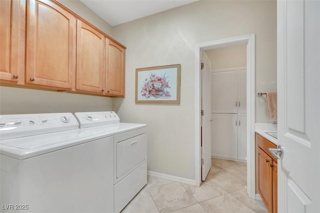 clothes washing area with independent washer and dryer, cabinet space, light tile patterned floors, and baseboards