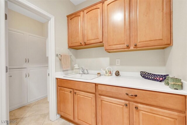 laundry area featuring a sink and light tile patterned flooring