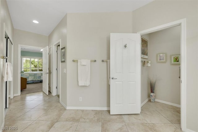 ensuite bathroom featuring tile patterned flooring and baseboards
