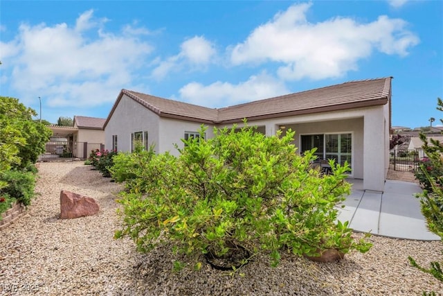 rear view of property featuring fence, stucco siding, and a tiled roof
