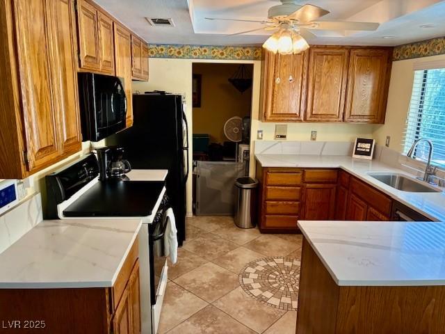 kitchen featuring a sink, range with electric cooktop, black microwave, brown cabinetry, and a ceiling fan