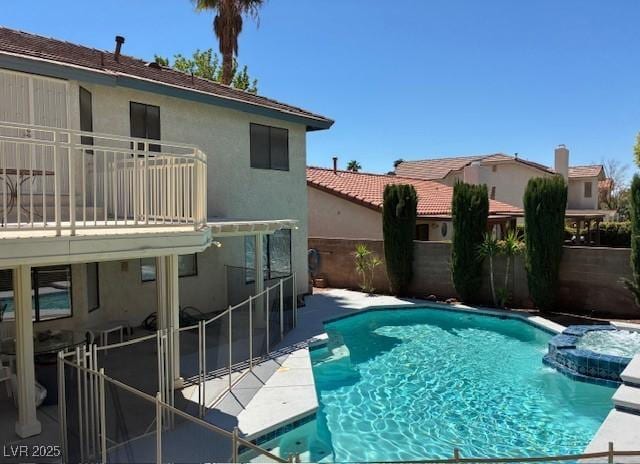 view of pool featuring a pool with connected hot tub, a patio area, and fence