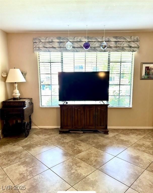 living area with plenty of natural light, baseboards, and light tile patterned floors