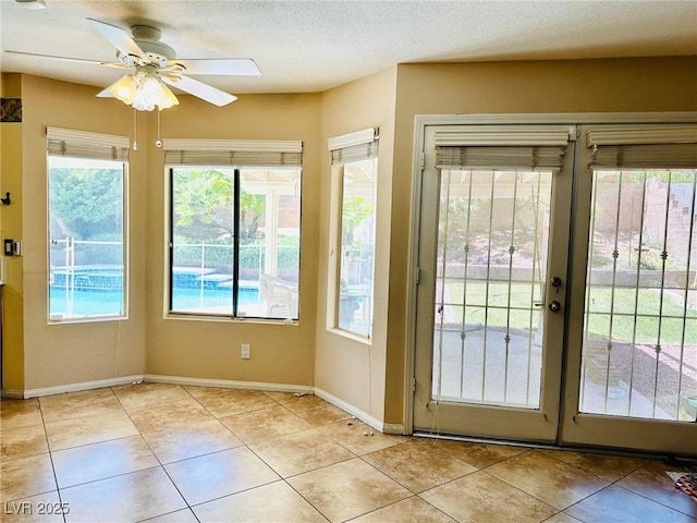 entryway with ceiling fan, light tile patterned floors, baseboards, french doors, and a textured ceiling