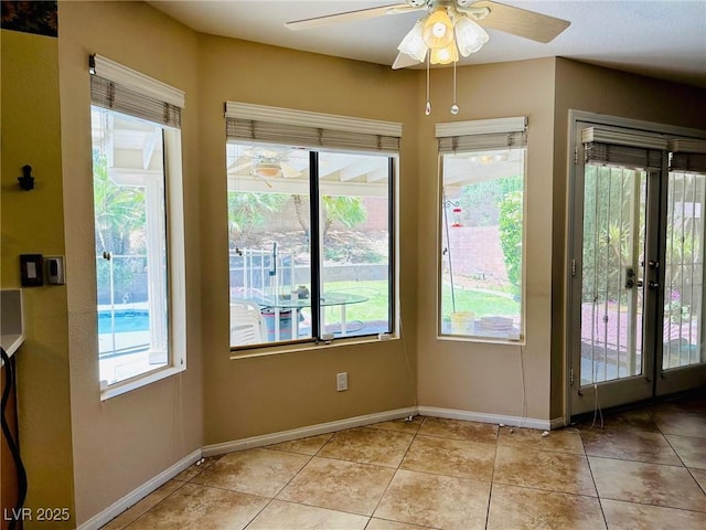 doorway featuring a ceiling fan, baseboards, and light tile patterned floors