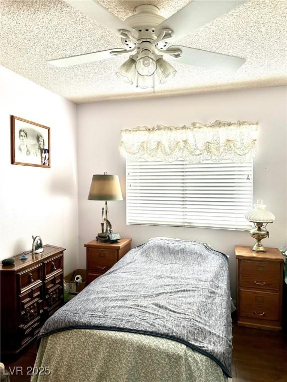 bedroom featuring dark wood-style flooring, a textured ceiling, and ceiling fan