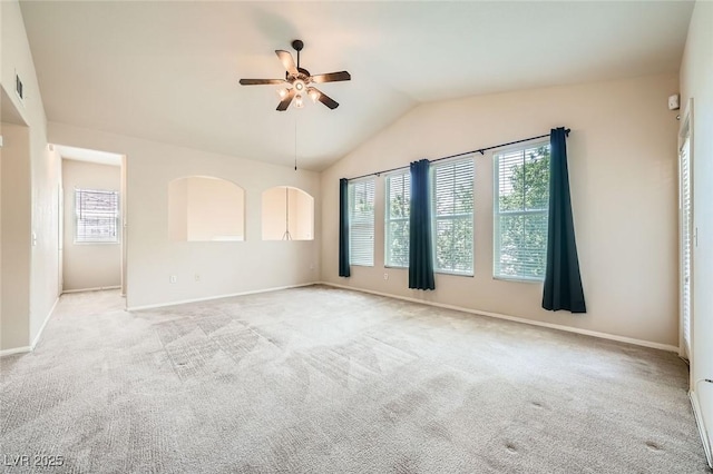 empty room featuring healthy amount of natural light, ceiling fan, vaulted ceiling, and light colored carpet