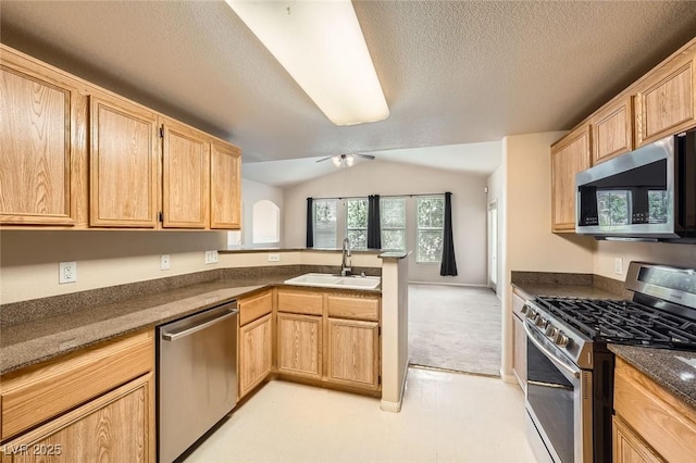 kitchen featuring appliances with stainless steel finishes, a sink, a peninsula, ceiling fan, and light carpet
