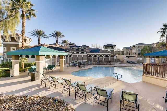 community pool with fence, a patio area, and a residential view