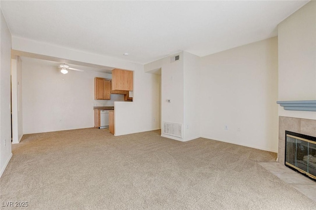 unfurnished living room featuring a fireplace, light colored carpet, and a ceiling fan