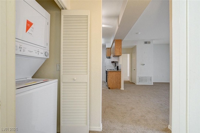washroom with stacked washer / dryer, light carpet, and baseboards
