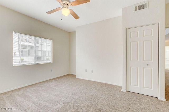 carpeted spare room featuring ceiling fan and baseboards