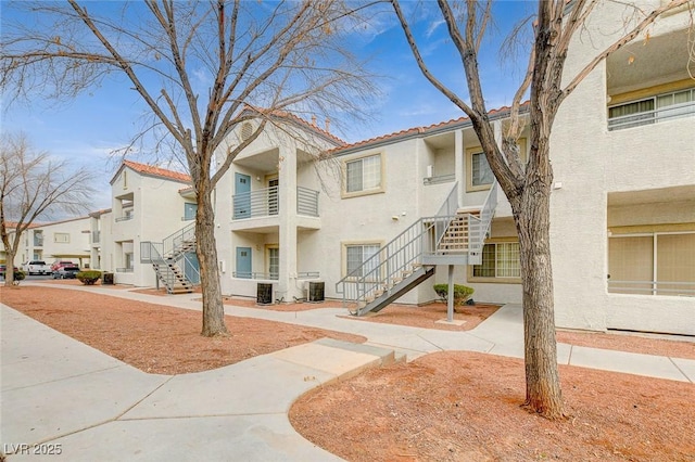 view of building exterior featuring stairs, central AC unit, and a residential view