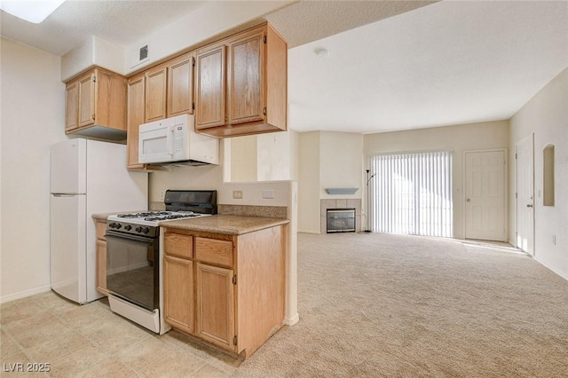 kitchen with white appliances, light countertops, light carpet, baseboards, and a tile fireplace