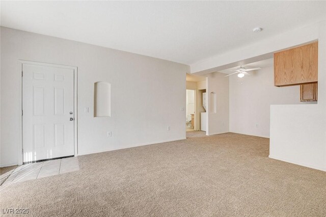 unfurnished living room with ceiling fan, light carpet, and baseboards