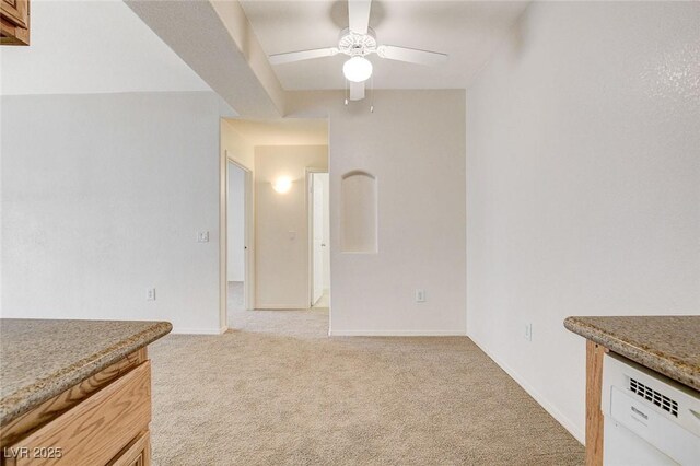 unfurnished dining area with light colored carpet, a ceiling fan, and baseboards