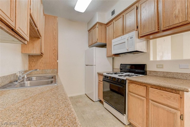 kitchen featuring white appliances, a sink, light countertops, light brown cabinetry, and baseboards