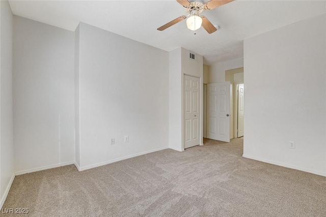carpeted spare room featuring a ceiling fan and baseboards