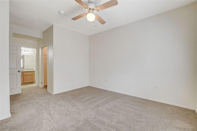 unfurnished bedroom with light carpet, baseboards, a ceiling fan, and ensuite bath