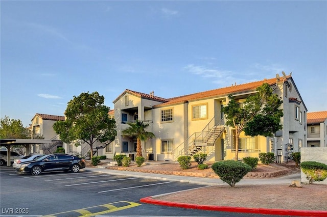 view of building exterior with uncovered parking and stairway