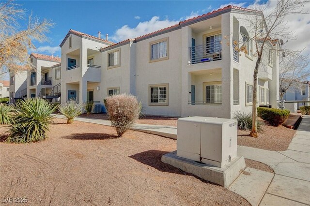 rear view of house with a tile roof and stucco siding