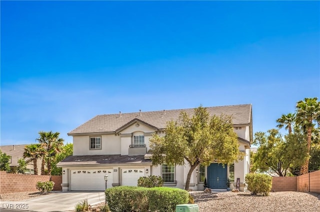 traditional home featuring fence, concrete driveway, an attached garage, and stucco siding
