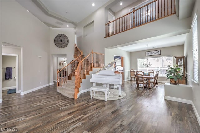 foyer featuring a towering ceiling, stairs, wood finished floors, baseboards, and recessed lighting