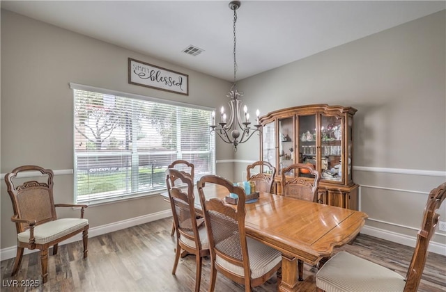 dining room with a chandelier, wood finished floors, and baseboards