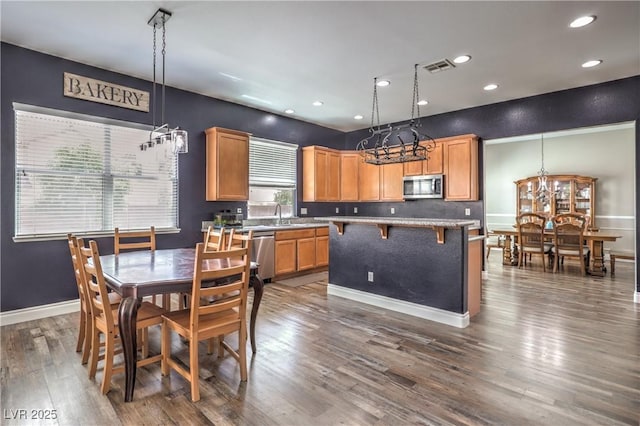 kitchen featuring a chandelier, stainless steel appliances, dark wood-style floors, a kitchen island, and recessed lighting