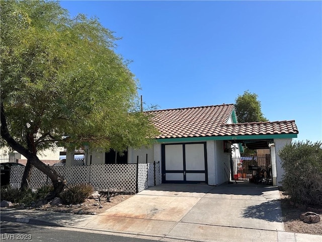 view of front facade featuring stucco siding, fence, and a tiled roof