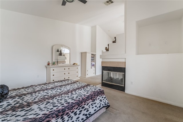 carpeted bedroom featuring a tile fireplace and ceiling fan