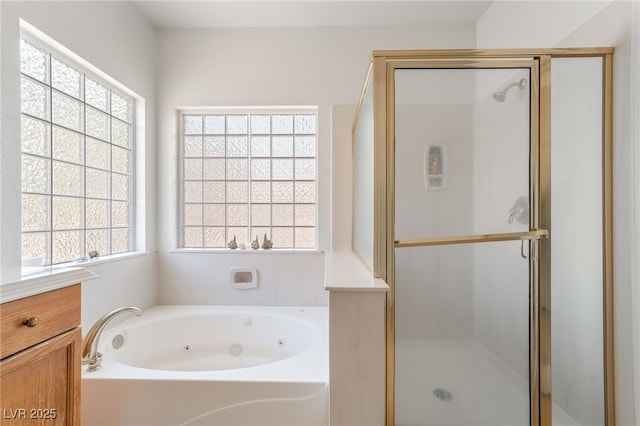 bathroom with a tub with jets, a stall shower, and vanity