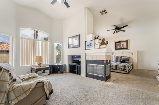 carpeted living area featuring a ceiling fan, high vaulted ceiling, and a tile fireplace