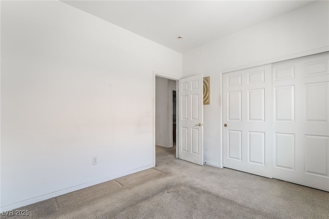 unfurnished bedroom with carpet, a closet, and baseboards