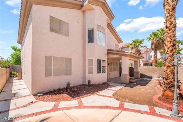 rear view of property with stucco siding, a patio area, and a fenced backyard
