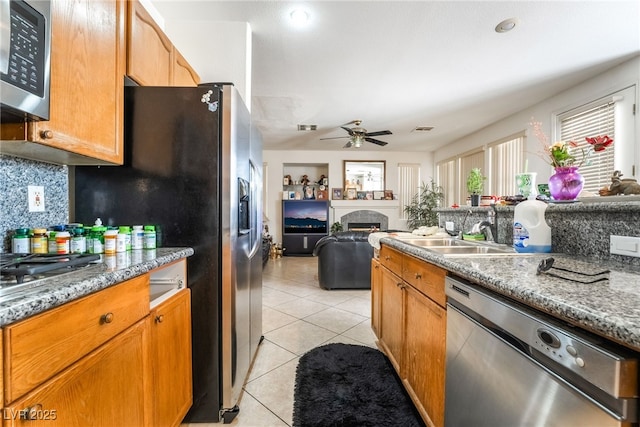 kitchen with appliances with stainless steel finishes, a sink, a fireplace, and open floor plan