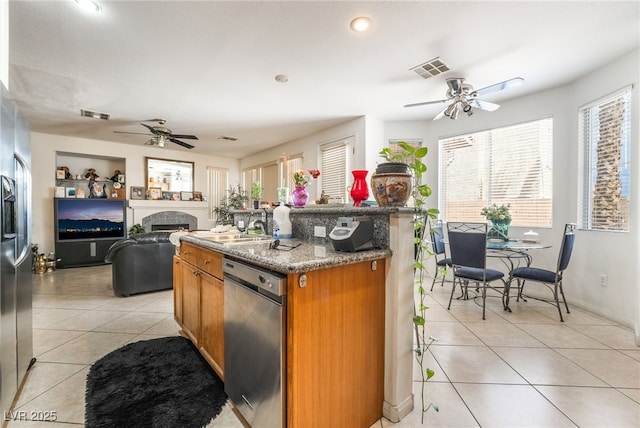 kitchen featuring ceiling fan, stainless steel dishwasher, light tile patterned floors, brown cabinets, and recessed lighting