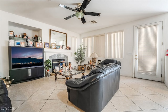 living area featuring a ceiling fan, light tile patterned floors, and a fireplace
