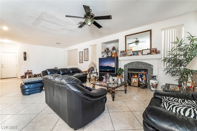 living room with light tile patterned floors, ceiling fan, and a glass covered fireplace