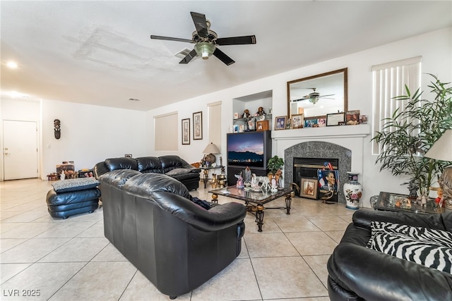 living area with a ceiling fan, light tile patterned floors, and a glass covered fireplace