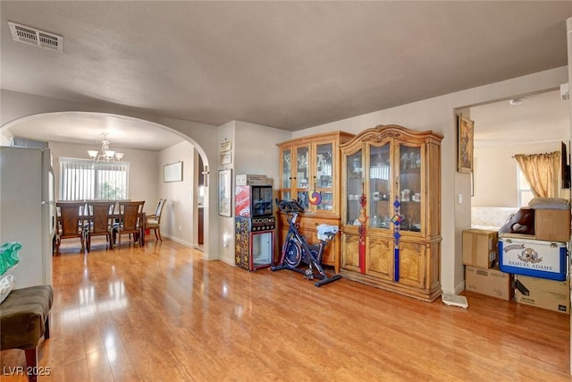 9065 W Torino Ave, Las Vegas, NV 89148 - living room featuring arched walkways, light wood-style floors, a chandelier, and baseboards