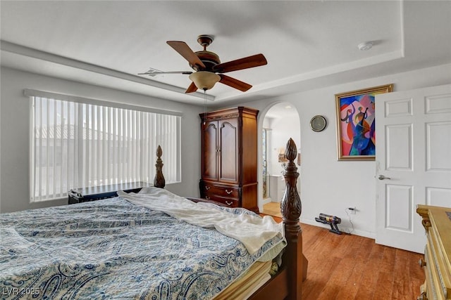 9065 W Torino Ave, Las Vegas, NV 89148 - bedroom featuring light wood finished floors, a raised ceiling, arched walkways, a ceiling fan, and baseboards