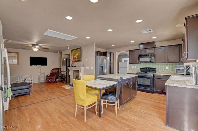 9065 W Torino Ave, Las Vegas, NV 89148 - kitchen with black appliances, arched walkways, a kitchen island, light wood-style flooring, and dark brown cabinets