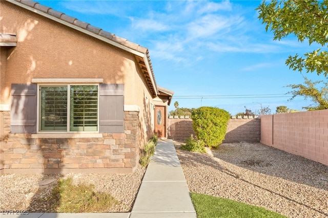 2720 Mickey Mantle Ct, Las Vegas, NV 89108 - view of side of property with stone siding, a fenced backyard, stucco siding, and a tiled roof