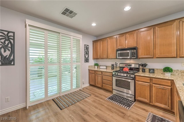 kitchen featuring stainless steel appliances, baseboards, light wood-type flooring, brown cabinets, and recessed lighting