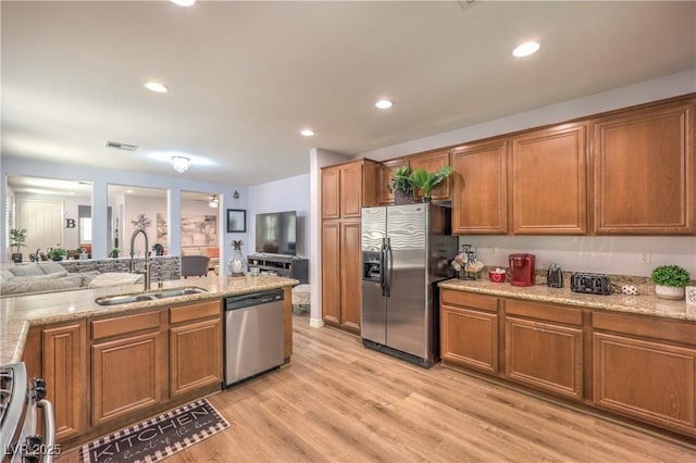 kitchen with appliances with stainless steel finishes, a sink, brown cabinetry, and recessed lighting