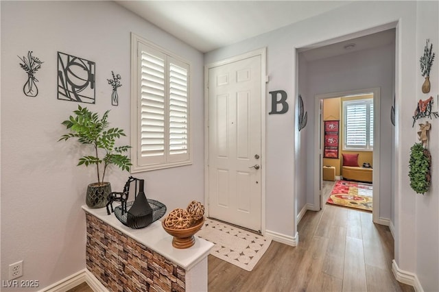 foyer with light wood-style floors and baseboards