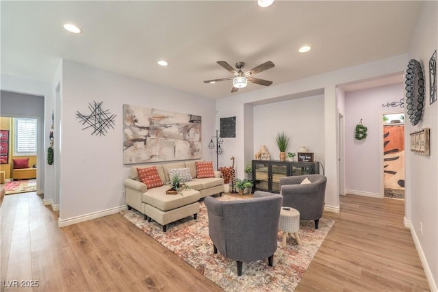 living area with light wood-type flooring, a ceiling fan, baseboards, and recessed lighting